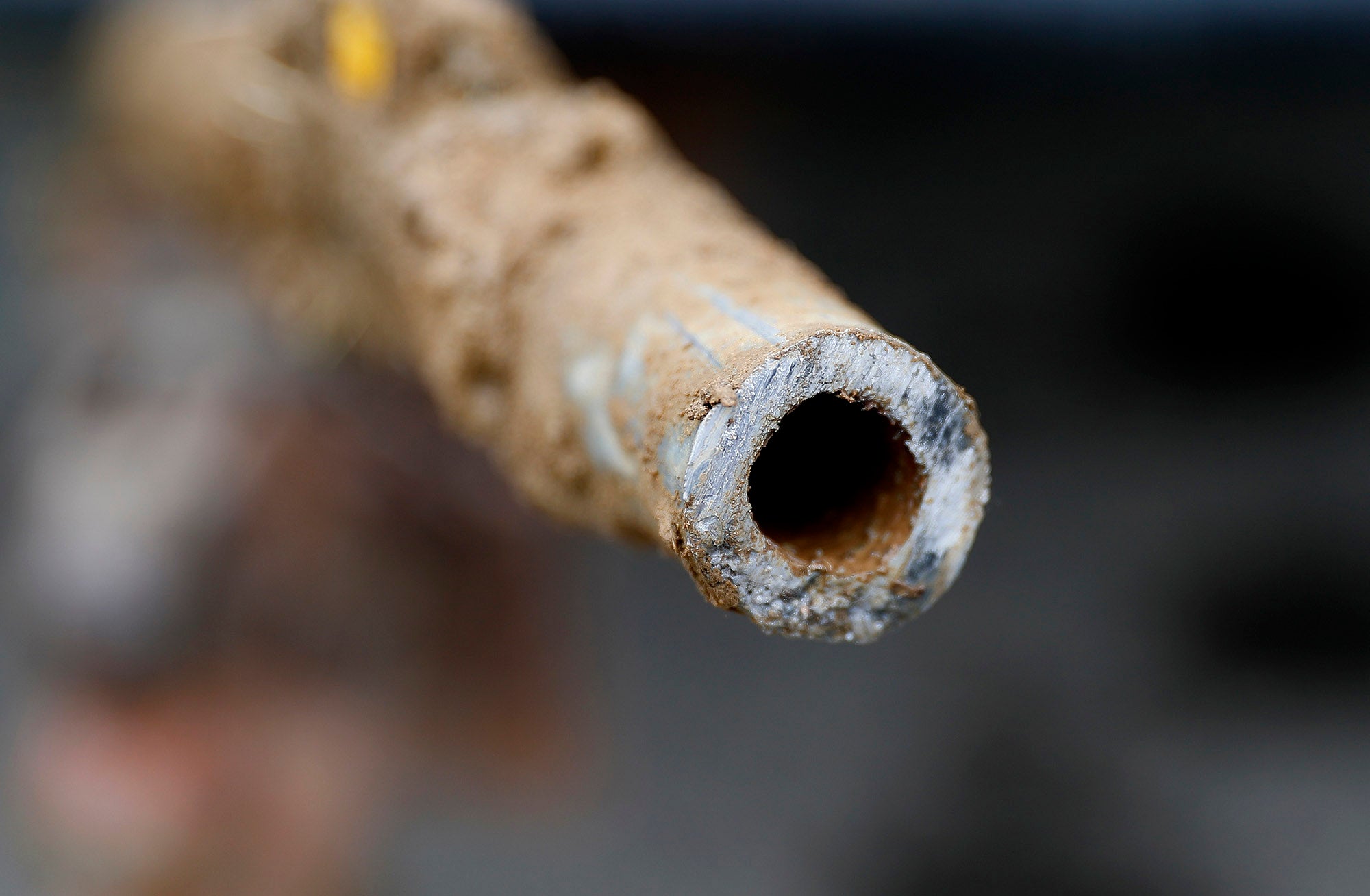 A close up picture of the open side of a dirty metal pipe that has been cut in half.